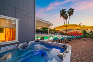 Ein Whirlpool mit Pool und Liegestühlen, ein Wandgemälde und Palmen.