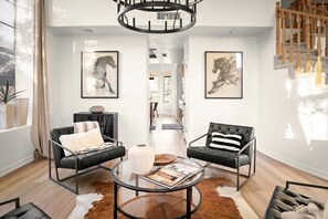 A modern living room with two leather armchairs, a glass coffee table, a cowhide rug, and artwork on the walls. - Lakeside 5BR Retreat Pool Hot Tub (Glendale)