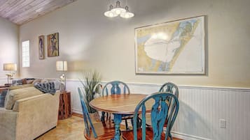 A dining area with a wooden table and blue chairs, a cream-colored sofa, and a map on the wall.