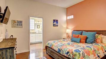A bedroom with a wooden bed, a nightstand, a wall-mounted lamp, and a door leading to a bathroom.