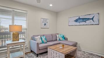 A living room with a sofa, a coffee table, a lamp, and a wall-mounted artwork.
