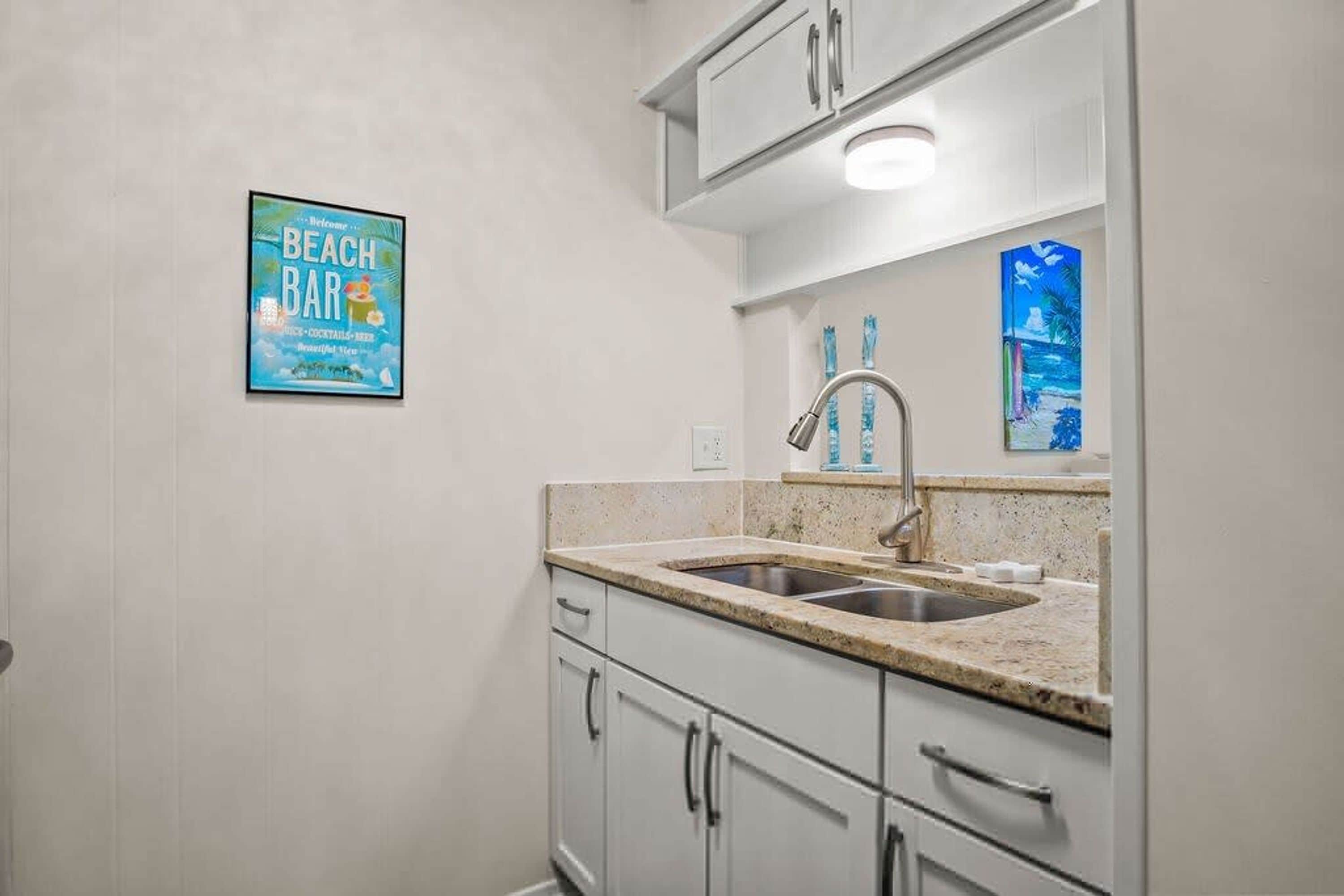 A kitchen with a sink, cabinets, and a countertop.