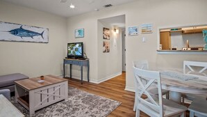A living room with a ceiling fan, a television, and artwork on the walls. - Seagull 26- Newly Renovated Close to Beach (Port Aransas)
