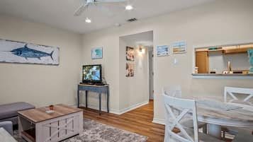 A living room with a ceiling fan, a television, and artwork on the walls.