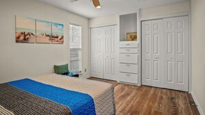 A bedroom with a bed, a ceiling fan, a window with blinds, and a set of white doors. - Seagull 26- Newly Renovated Close to Beach (Port Aransas)
