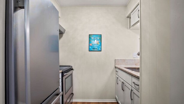 A narrow kitchen with a refrigerator, oven, and sink. - Seagull 26- Newly Renovated Close to Beach (Port Aransas)