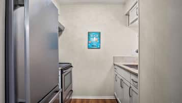 A narrow kitchen with a refrigerator, oven, and sink.