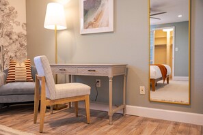 A hotel room with a wooden desk, a chair, a sofa, a lamp, and a bed with a mirror reflecting the room. - Minutes to Anna Maria Island Pool Mini Golf (Bradenton)