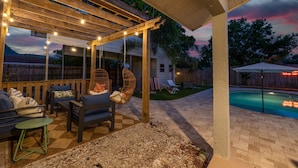 A covered outdoor patio with string lights, a pool, and a wooden deck. - Minutes to Anna Maria Island Pool Mini Golf (Bradenton)