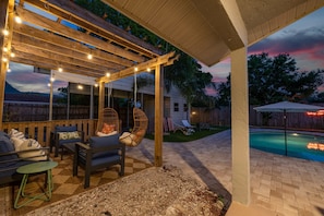 Eine überdachte Terrasse im Freien mit Lichterketten, einem Pool und einem Holzdeck.