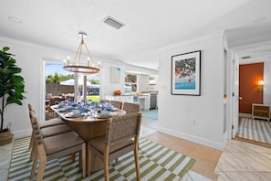 A dining area with a round table, chairs, and a hanging light fixture. - Minutes to Anna Maria Island Pool Mini Golf (Bradenton)