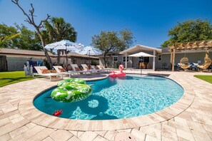 A backyard with a swimming pool, lounge chairs, and inflatable toys. - Minutes to Anna Maria Island Pool Mini Golf (Bradenton)