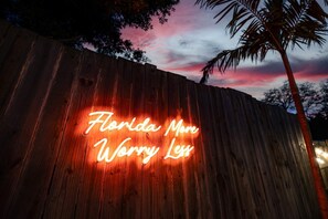 A wooden fence with a neon sign that reads 'Florida More Worry Less'. - Minutes to Anna Maria Island Pool Mini Golf (Bradenton)