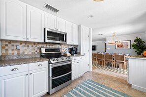 A modern kitchen with white cabinetry, a stainless steel range, an oven, a microwave, and a coffee maker. - Minutes to Anna Maria Island Pool Mini Golf (Bradenton)