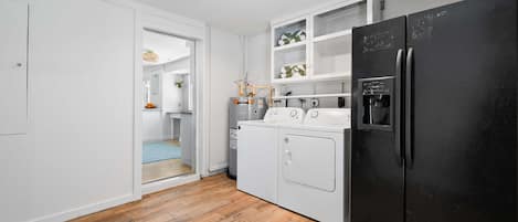 Una cocina compacta con un refrigerador negro, una estufa y una lavadora.