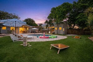 A backyard with a swimming pool, lounge chairs, a wooden deck, and a small play area. - Minutes to Anna Maria Island Pool Mini Golf (Bradenton)
