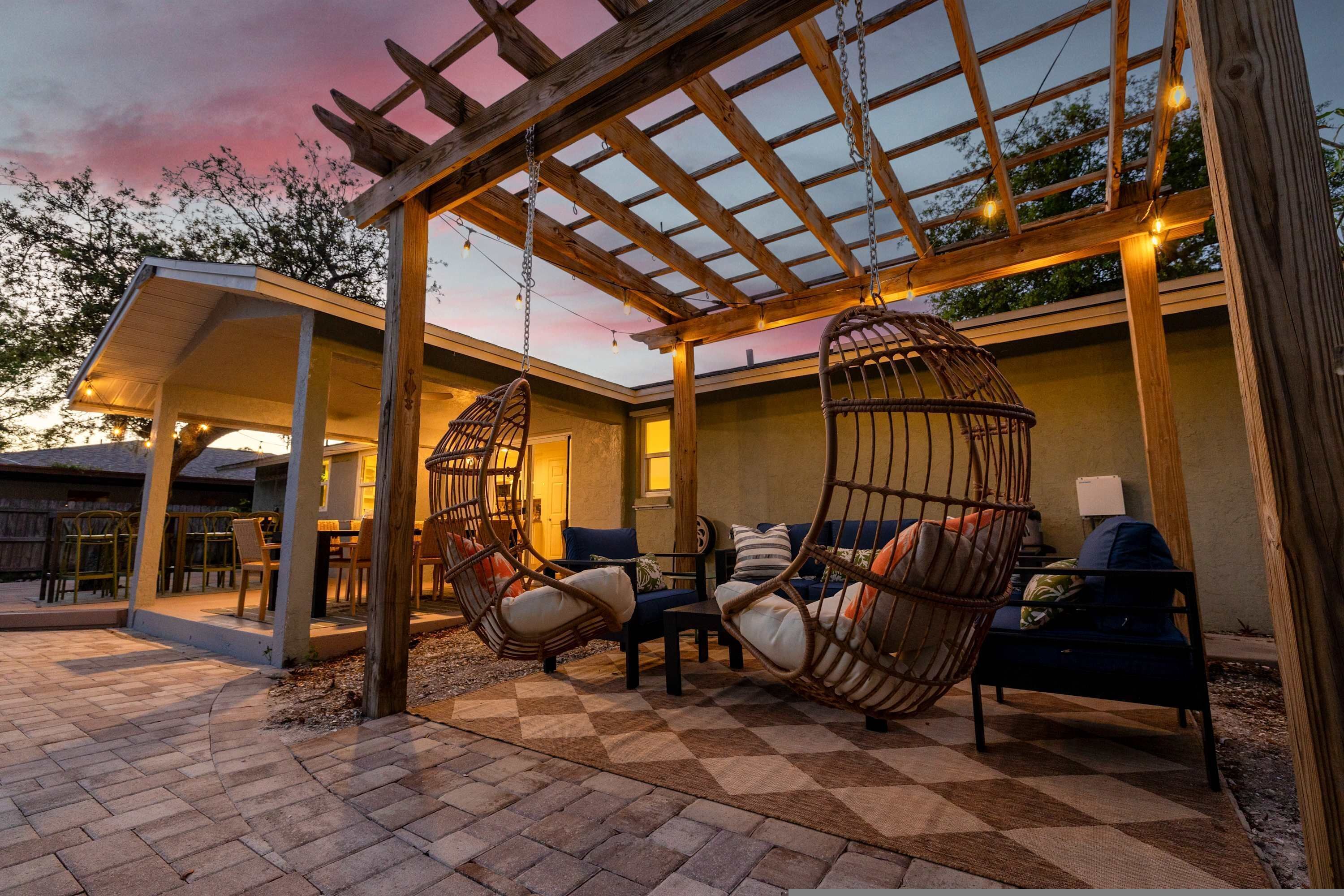 A covered outdoor seating area with wicker chairs and a checkered floor.
