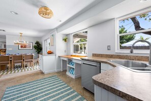 Eine moderne Küche mit Granitabdeckung, Spüle aus Edelstahl und einem Essbereich mit kariertem Teppich.