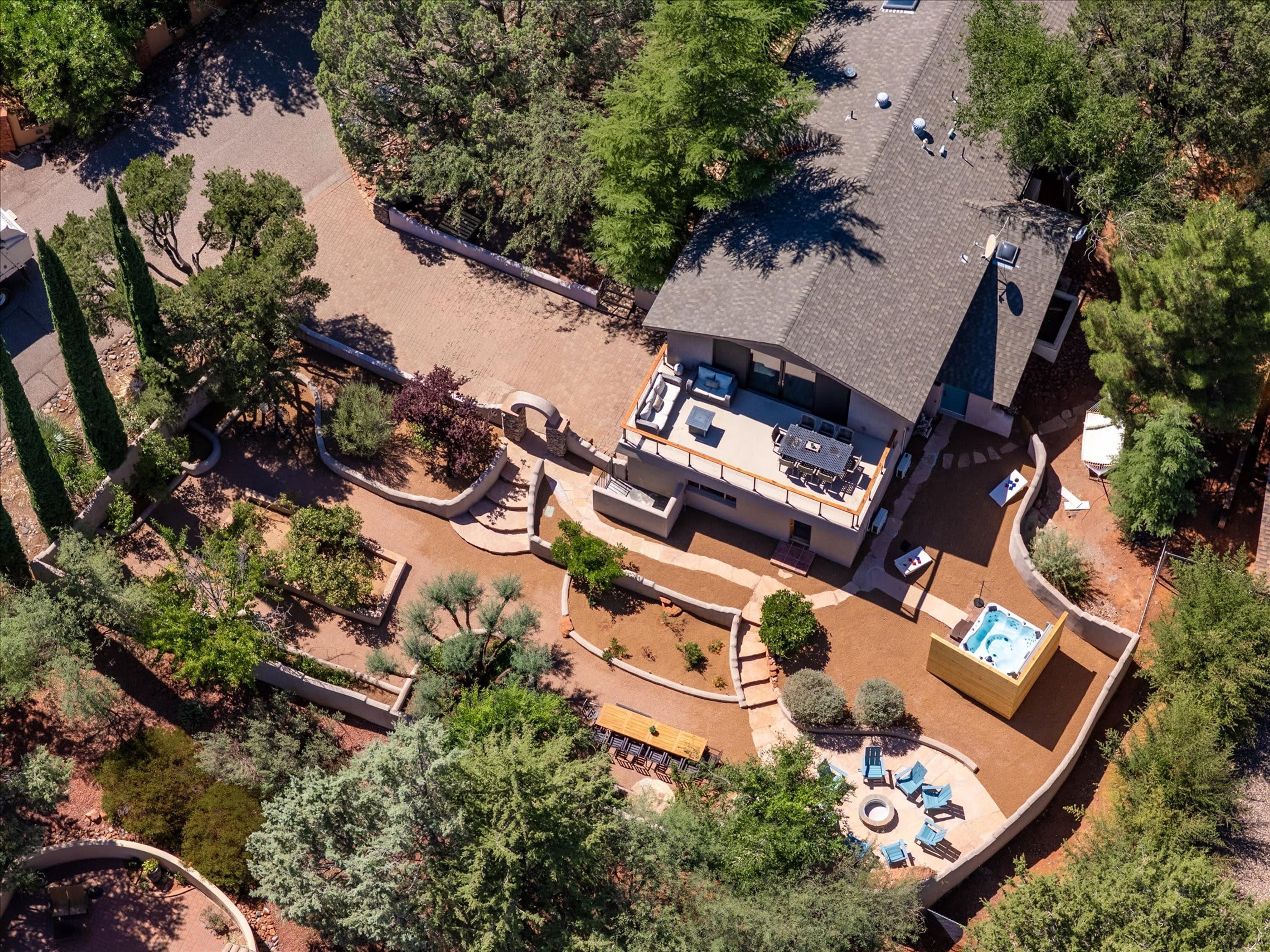 An aerial view of a residential property with a swimming pool, patio furniture, and a landscaped garden.