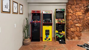 A row of arcade machines in a room with a stone wall and framed pictures on the wall. - The Sedona Sanctuary Hot Tub Unbeatable Views (Sedona)