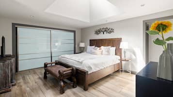 A bedroom with a bed, bedside tables, a chair, a desk, and a large window.