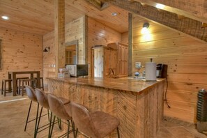 Un interior de madera con una zona de bar, asientos y una cocina.