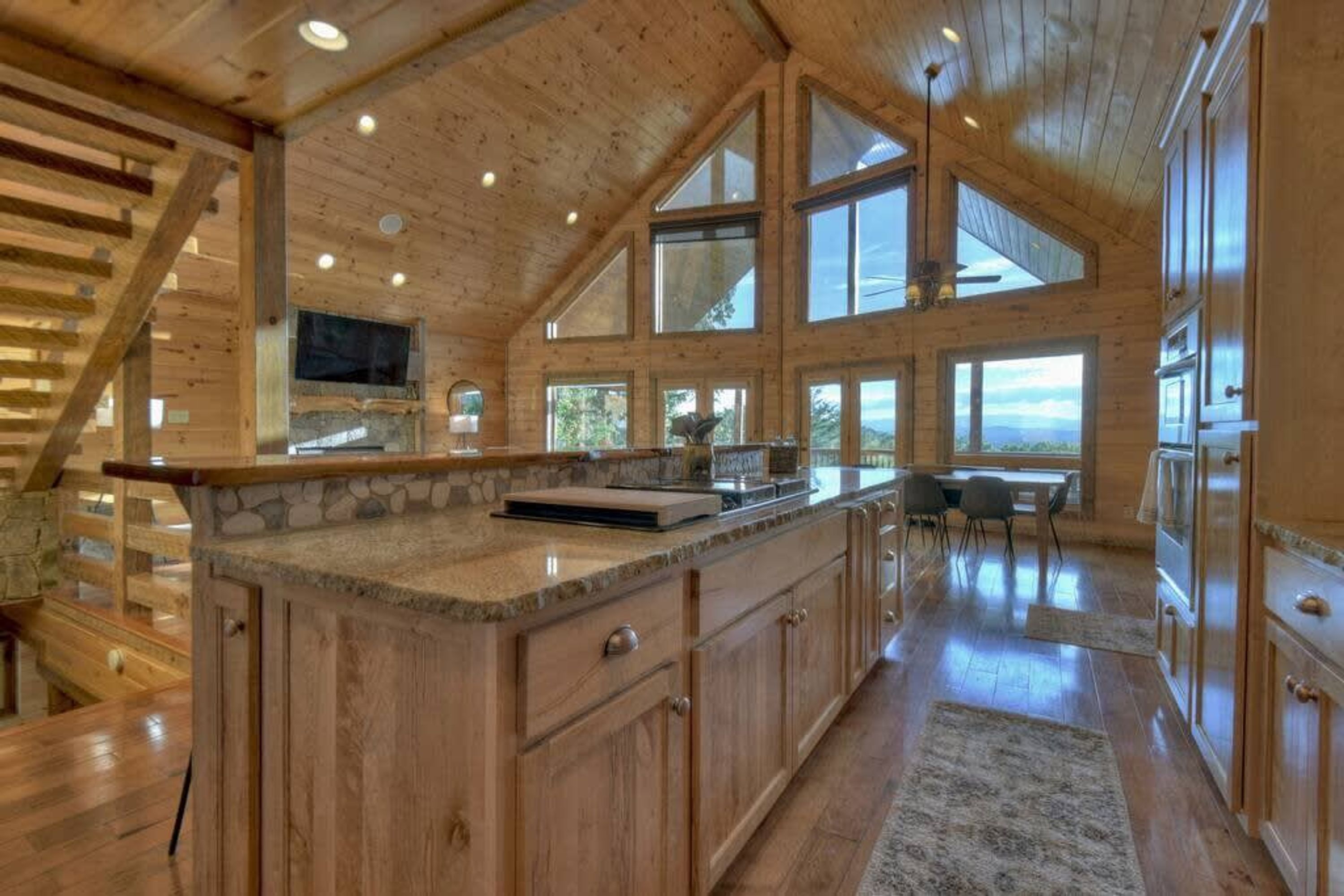 A spacious kitchen with a large island, wooden cabinetry, and a stone countertop.