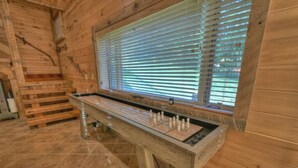 A wooden-floored room with a foosball table and a window with blinds. - Endless Views Hot Tub Movie Theater Firepit (Mineral Bluff)