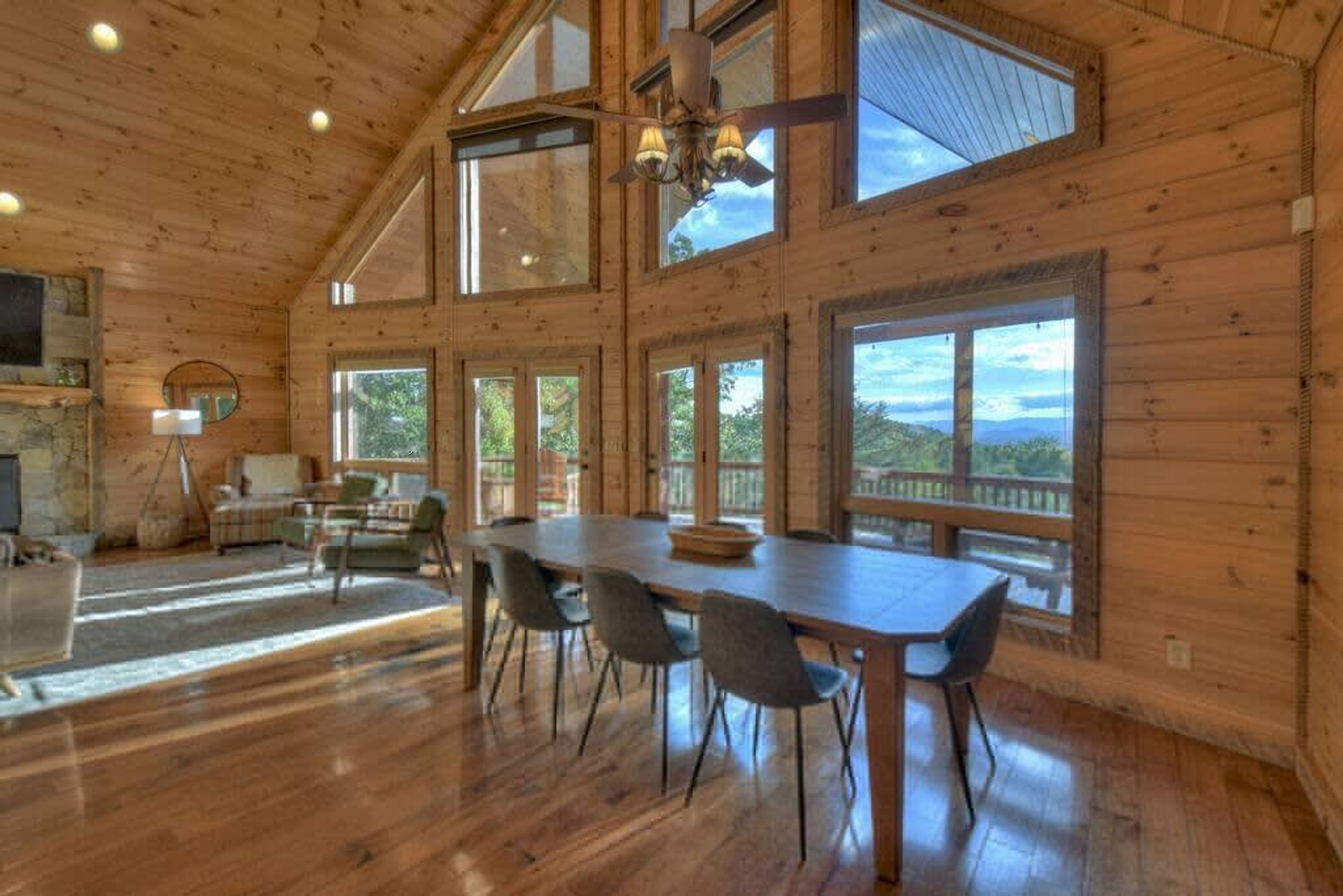 Una habitación amplia con una gran mesa de comedor y sillas, chimenea y ventanas que ofrecen vistas al exterior.