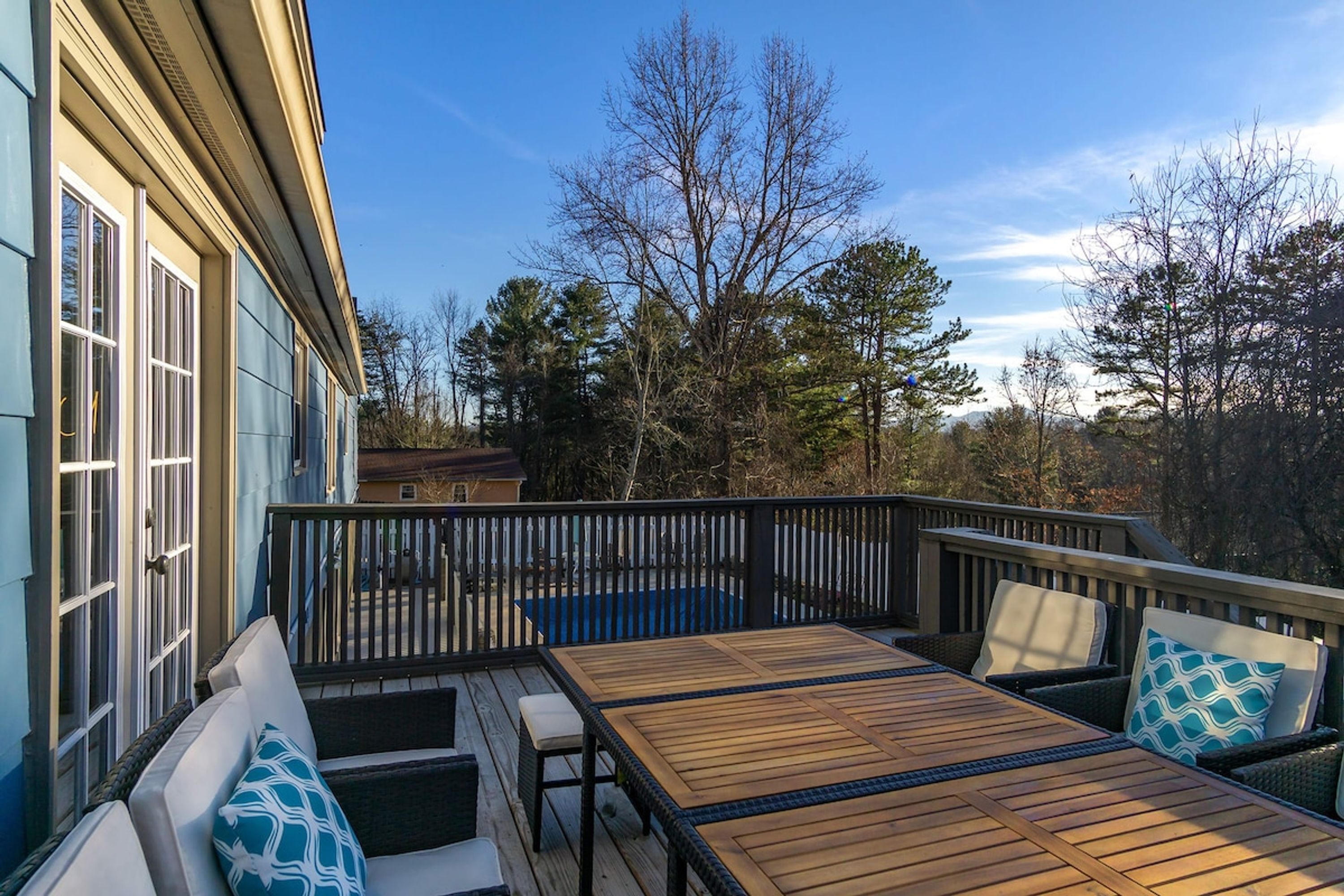 A wooden deck with a table and chairs, surrounded by a black railing.