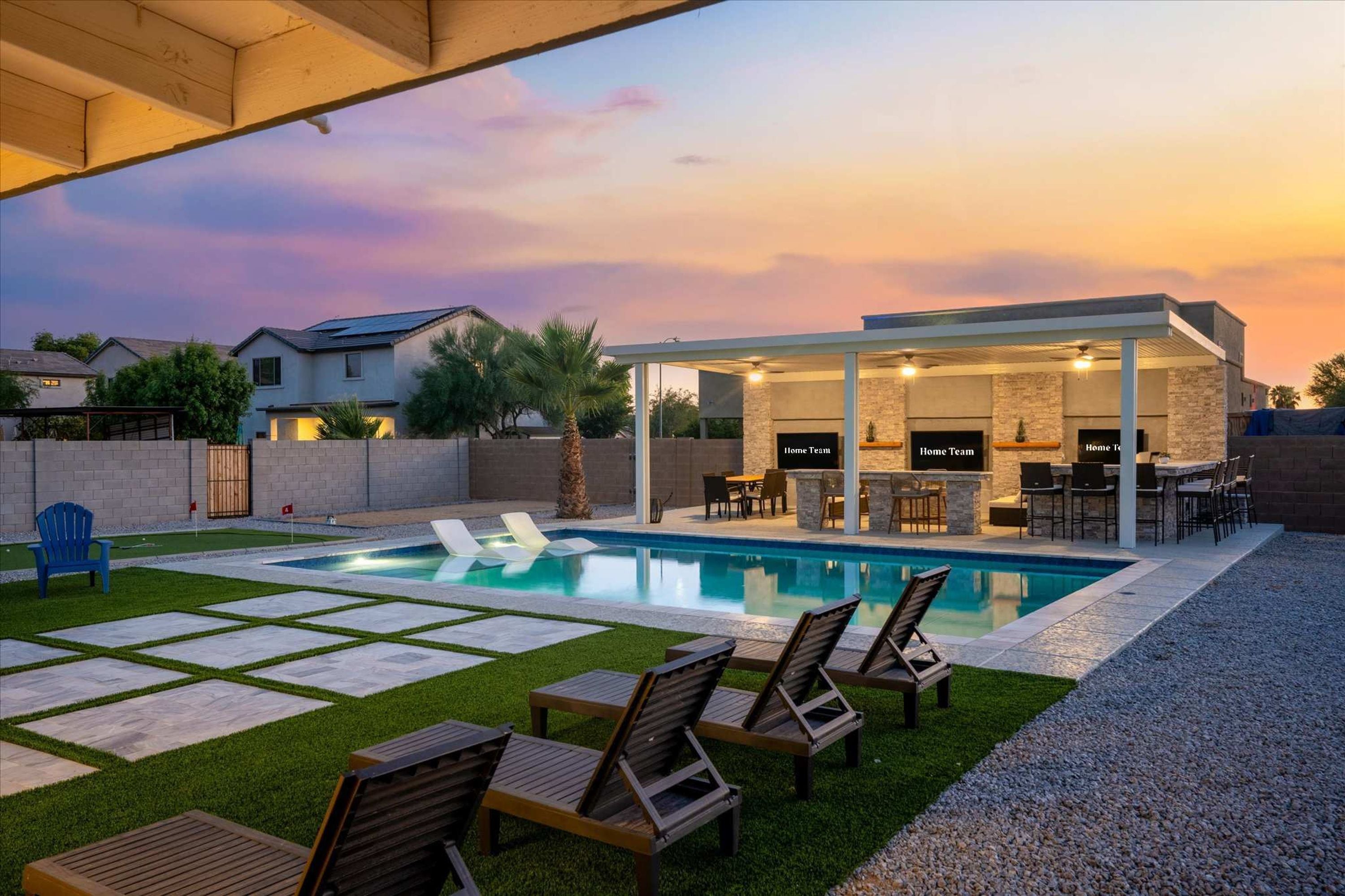 A modern outdoor pool area with a covered seating area and a barbecue station.