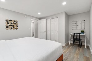 A bedroom with a bed, a desk with a chair, and a wall-mounted shelf with a plant. - The Palm Putt Heated Pool Golden Tee Bocce (Phoenix)