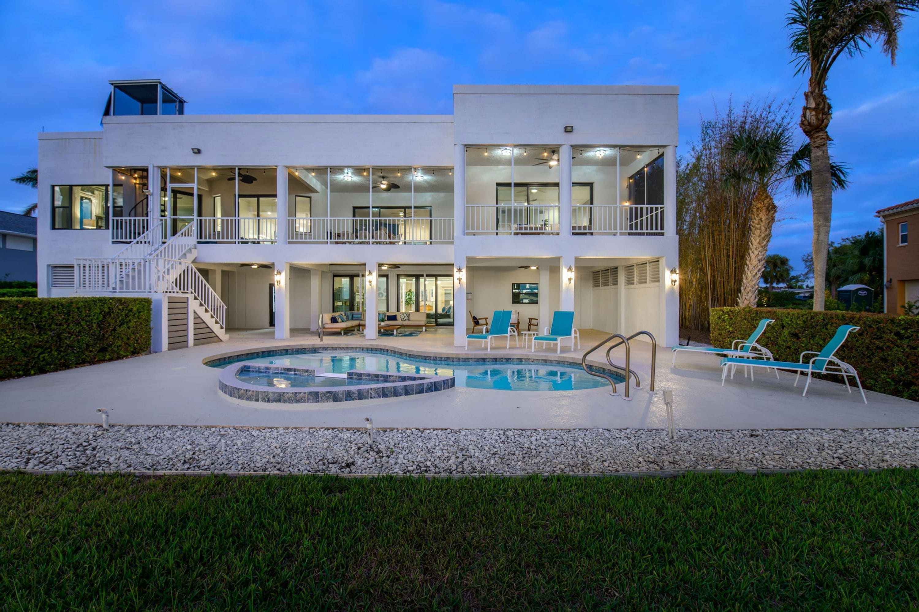 Ein zweistöckiges Haus mit Swimmingpool, Außenbereich mit Sitzgelegenheit und einer Treppe, die zum oberen Stockwerk führt.