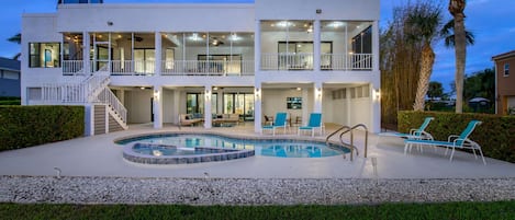 Una casa de dos pisos con piscina, mobiliario de exterior y una escalera que conduce al nivel superior.