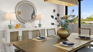 A dining area with a wooden table, two chairs, a large mirror, and a vase with decorative flowers. - Luxury Beachfront Retreat Pool Game Room Sleeps 16 (Bradenton)