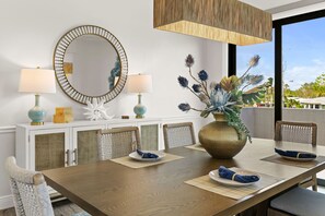 Ein Essbereich mit einem Holztisch, zwei Stühlen, einem großen Spiegel und einer Vase mit dekorativen Blumen.