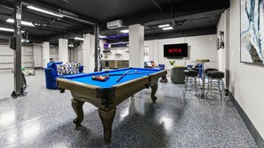 A pool table in a modern indoor space with a Netflix sign, a bar area, and a sofa. - Luxury Beachfront Retreat Pool Game Room Sleeps 16 (Bradenton)