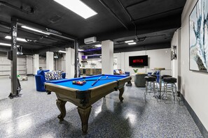 Ein Billardtisch in einem modernen Innenraum mit einem Netflix-Schild, einer Bar und einer Couch.