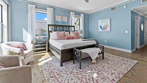 A bedroom with a bed, a ceiling fan, a window with curtains, a small table, and a chair. - Luxury Beachfront Retreat Pool Game Room Sleeps 16 (Bradenton)