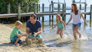 A family of four at a beach with a wooden pier and a sandy area for playing. - Luxury Beachfront Retreat Pool Game Room Sleeps 16 (Bradenton)
