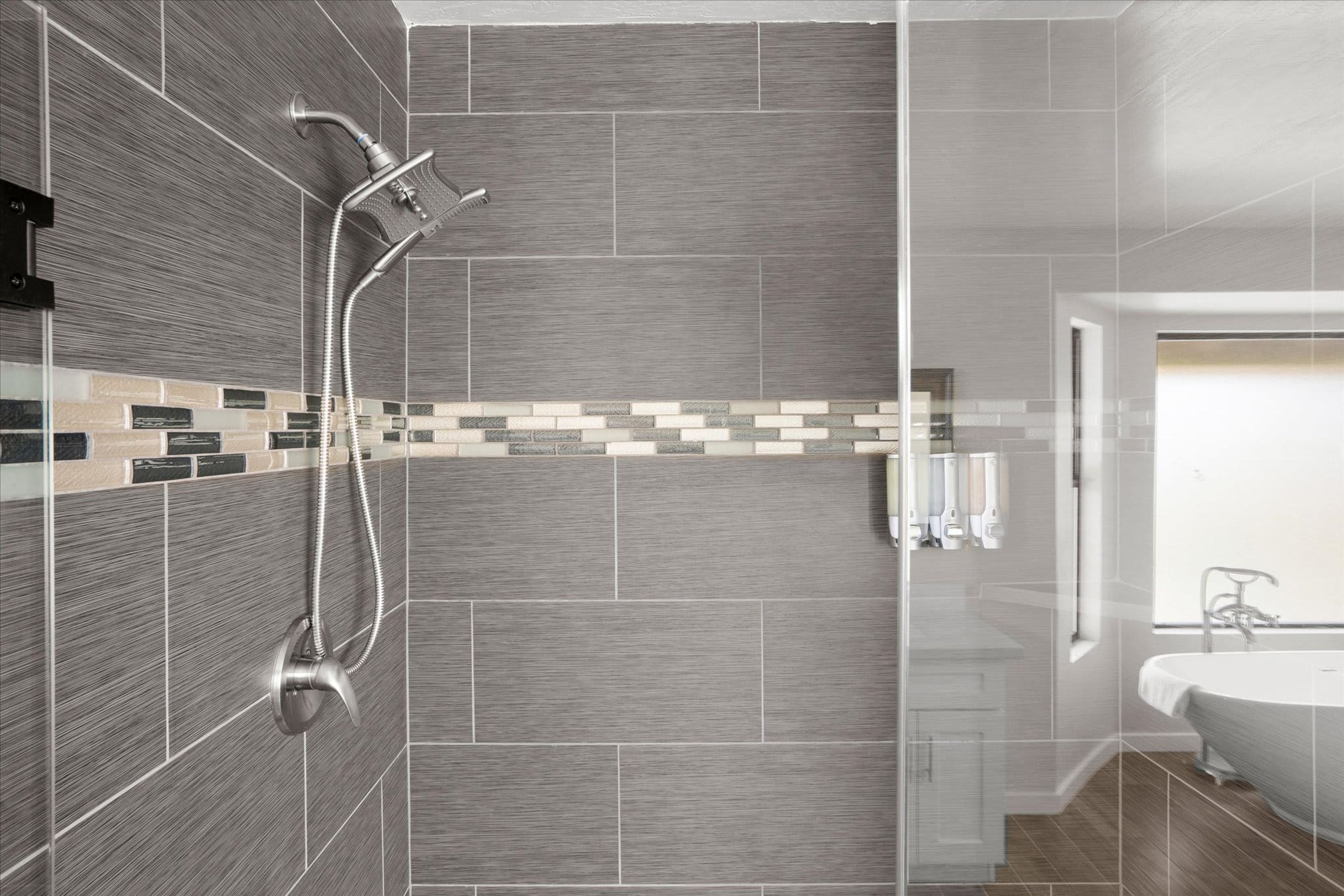 A modern bathroom with a shower, a tiled backsplash, and a sink.
