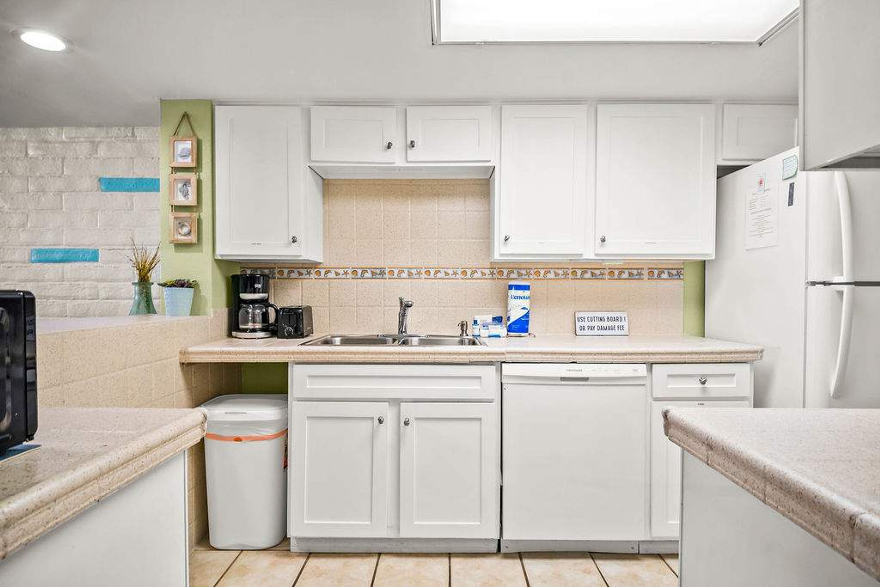 A modern kitchen with white cabinets, a sink, and a dishwasher.