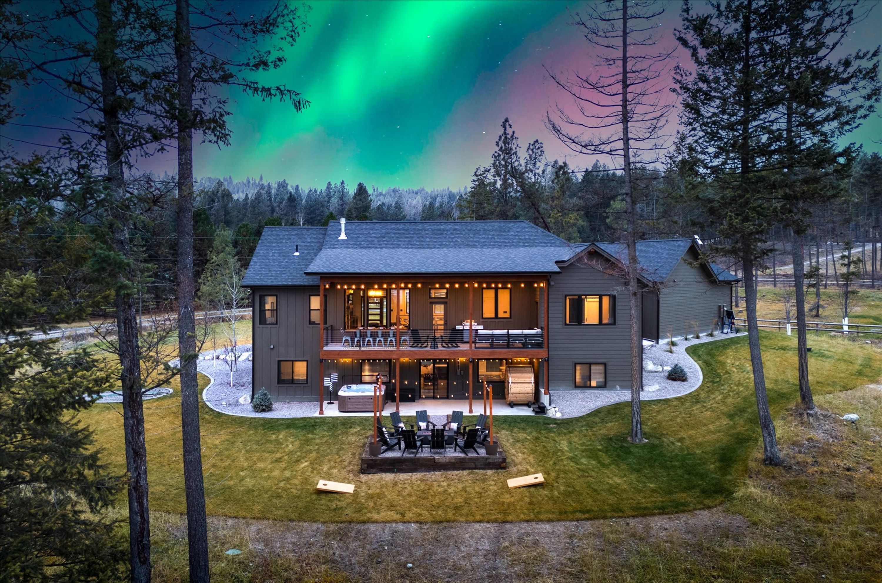 A two-story house with a balcony, a hot tub, and a deck with outdoor furniture.