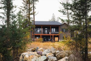 A two-story building with a balcony, surrounded by trees and rocks. - The Evergreen Close to Skiing Sauna Spa (Somers)