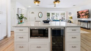 Una cocina moderna con una isla grande, horno empotrado y comedor con vistas.