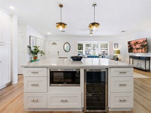 A modern kitchen with a large island, built-in oven, and a dining area with a view. - 4 Br Oasis Pool Tiki Hut Hot Tub Ping Pong Arcade (Seminole)
