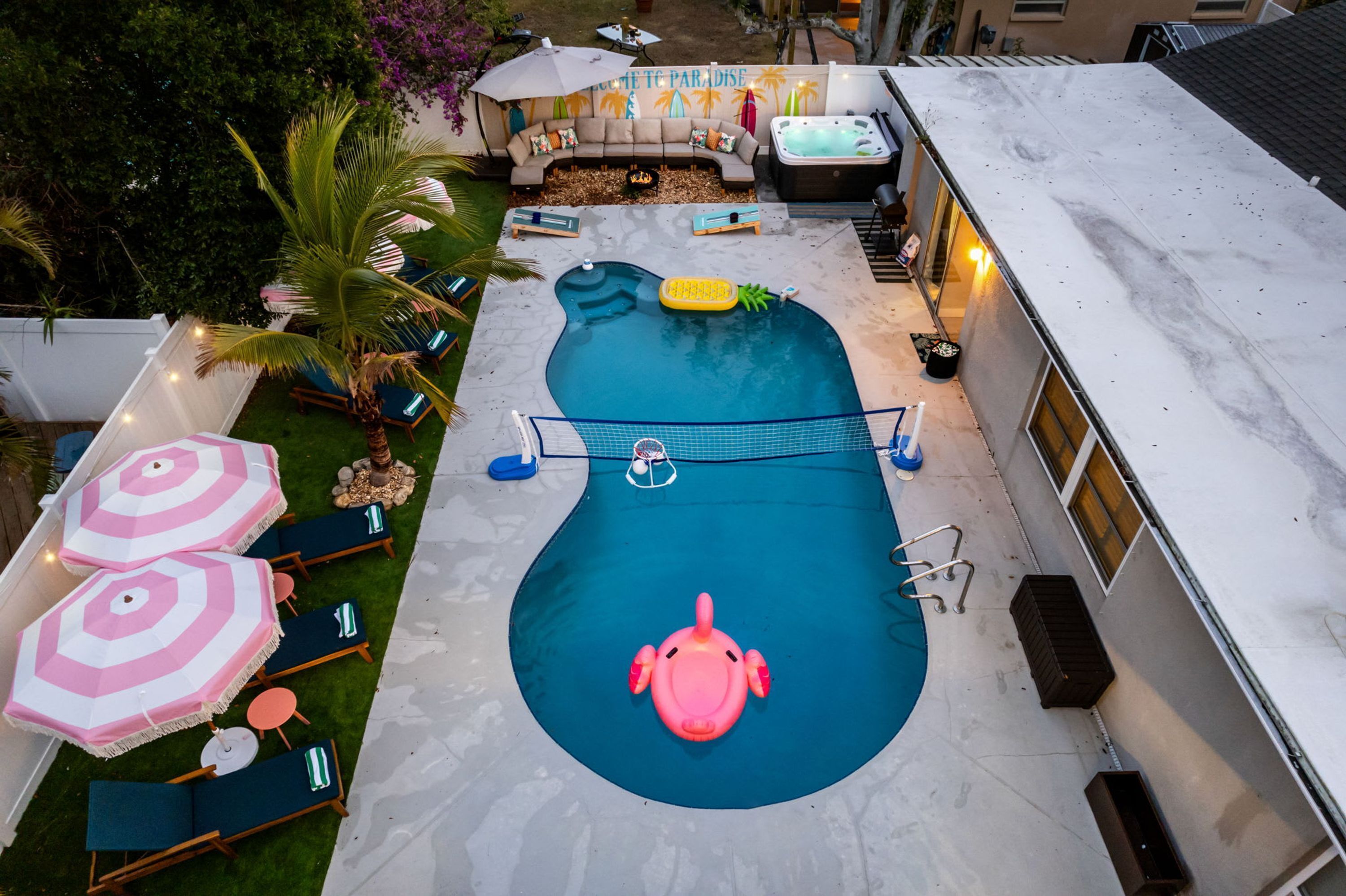 Una piscina con hidromasaje, sillas de descanso y un flamenco inflable pequeño.
