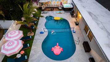 Una piscina con hidromasaje, sillas de descanso y un flamenco inflable pequeño.