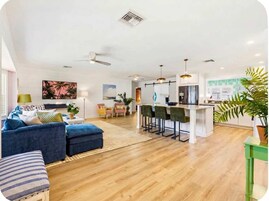 Una sala moderna con sofá, mesa de centro y comedor con taburetes de bar.