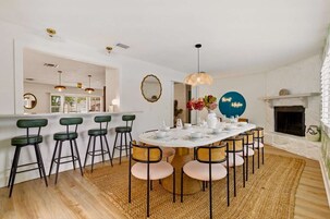 Un comedor con una mesa redonda, taburetes de bar y una chimenea.